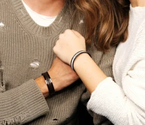 man and woman holding hands with matching bracelets