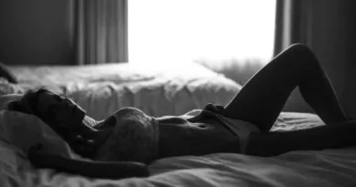 black and white photo of a woman lying on a bed in her underwear