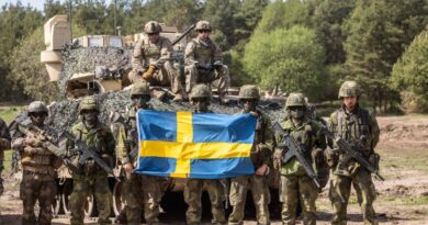 soldiers in front of a tank with the Swedish flag