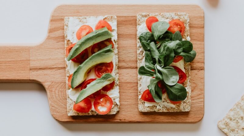 sandwich with avocado, tomatoes and spinach on a board